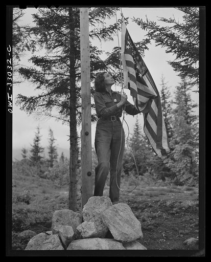 Gorham (vicinity), New Hampshire. Barbara Mortensen, a fire and airplane lookout on Pine Mountain, running up the colors