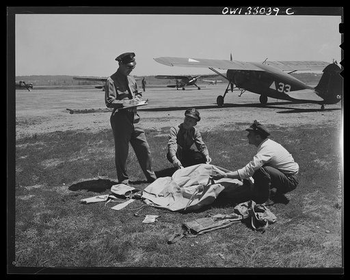 Bar Harbour, Maine. Civil Air Patrol base headquarters of coastal patrol no. 20. Officer checking the safety gear, which includes a rubber boat, a "Mae West" life preserver, flares, see andho, patching equipment for mending machine gun holes in the boat, a Very pistol, a flash light with red lens, a