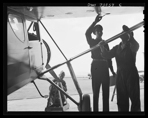 Untitled photo, possibly related to: Bar Harbor, Maine. Civil Air Patrol base headquarters of coastal patrol no. 20. The chief engineering officer conducting a routine check of patrol planes in the hanger