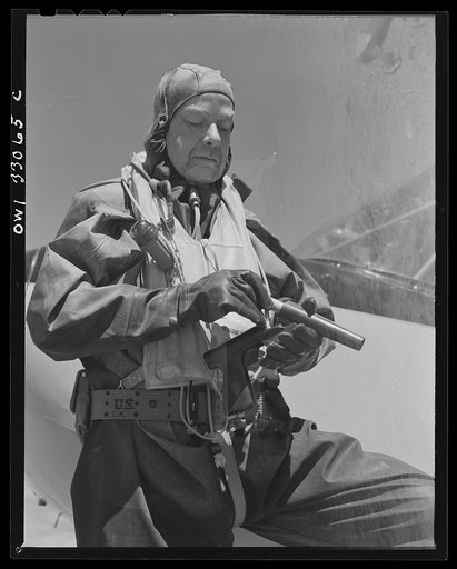 Bar Harbor, Maine. Civil Air Patrol base headquarters of coastal patrol no. 20. Flyer in a rubber crash suit loading a Very pistol before taking off