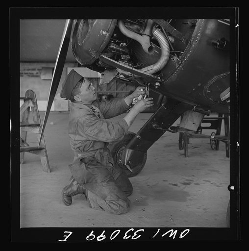 Bar Harbor, Maine. Civil Air Patrol base headquarters of coastal patrol no. 20. Ground crew mechanic making repairs on a patrol plane in the hangar