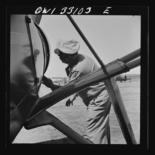 Untitled photo, possibly related to: Bar Harbor, Maine. Civil Air Patrol base headquarters of coastal patrol no. 20. The chief engineering officer conducting a routine check of patrol planes in the hanger
