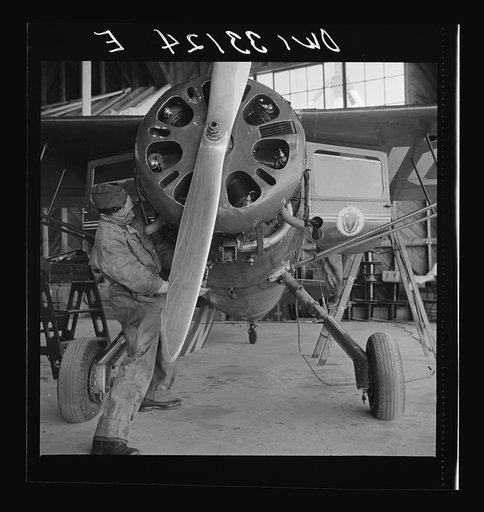 Bar Harbor, Maine. Civil Air Patrol base headquarters of coastal patrol no. 20. Ground crew mechanic working on a patrol plane in the hangar