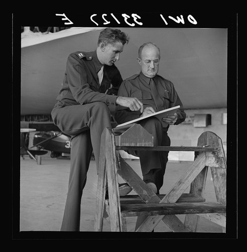 Bar Harbor, Maine. Civil Air Patrol base headquarters of coastal patrol no. 20. Chief engineering officer and radio expert checking reports in the hangar