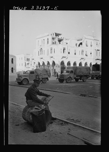 Tripoli, Libya. Lieutenant Milton Marx of New York City, attached to the public relations office of the U.S. Army 9th Air Force, doing some painting in the streets. In civilian life, Marx is a commercial artist