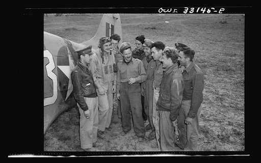 Major Glade B. Bilby of Skidmore, Montana talking to members of his flying squadron somewhere in Tunisia. While flying top cover, the squadron destroyed six German Messerschmitt