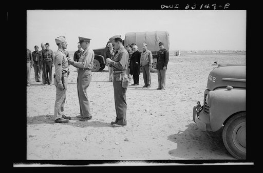 An American sergeant receiving a decoration during the North African campaign. Archbishop Spellman of New York is watching the ceremony