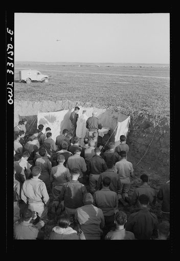 Archbishop Francis J. Spellman of New York touring the North African battle front, saying a mass for the men at the 57th Fighter Group of the U.S. Army 9th Air Force. This group, located "somewhere in Tunisia," knocked almost 100 Axis transports and fighters out of the skies in one engagement