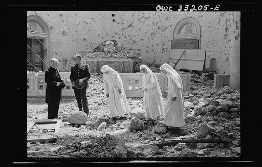 Tripoli, Libya. Archbishop Spellman of New York (left) surveys the ruins of the chapel of the Franciscan Missionaries of Mary. With him are Brigadier General Auby C. Strickland of the U.S. Army 9th Air Force and Catholic nuns