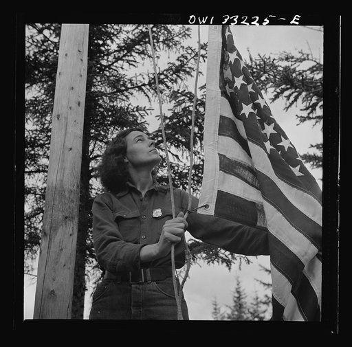 Gorham (vicinity), New Hamphire. Barbara Mortensen, a fire and airplane lookout on Pine Mountain, running up the colors