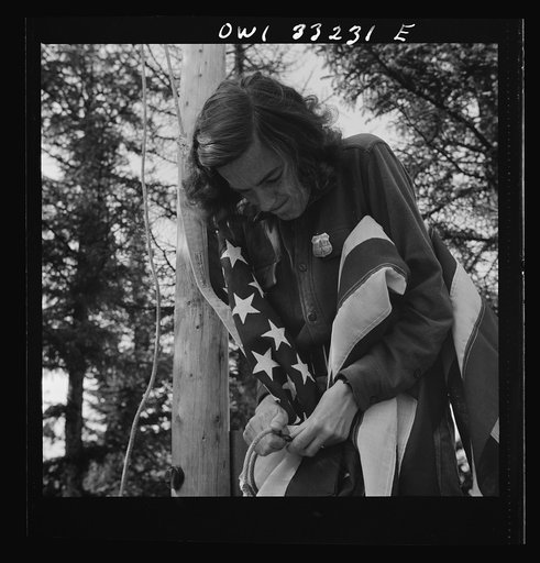 Gorham (vicinity), New Hampshire. Barbara Mortensen, a fire and airplane lookout on Pine Mountain, running up the colors