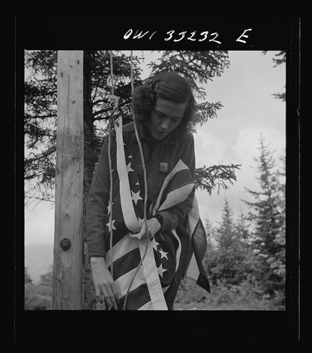Gorham (vicinity), New Hampshire. Barbara Mortensen, a fire and airplane lookout on Pine Mountain, running up the colors