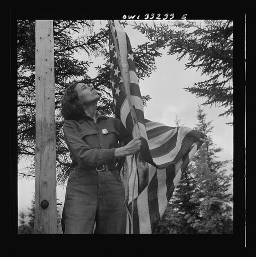 Gorham (vicinity), New Hampshire. Barbara Mortensen, a fire and airplane lookout on Pine Mountain, running up the colors
