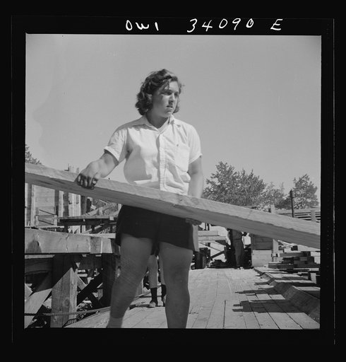 Untitled photo, possibly related to: Turkey Pond, near Concord, New Hampshire. Women workers employed by a U.S. Department of Agriculture timber salvage sawmill. Ruth De Roche, pit woman, placing a trimmed board on the proper pile in the pit