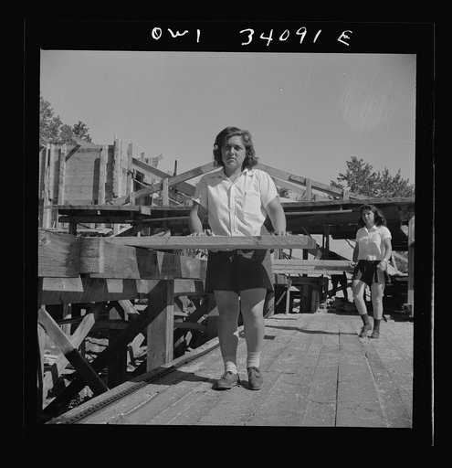 Untitled photo, possibly related to: Turkey Pond, near Concord, New Hampshire. Women workers employed by a U.S. Department of Agriculture timber salvage sawmill. Ruth De Roche, pit woman, placing a trimmed board on the proper pile in the pit