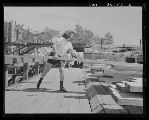 Untitled photo, possibly related to: Turkey Pond, near Concord, New Hampshire. Women workers employed by a U.S. Department of Agriculture timber salvage sawmill. Norma Webber, pit woman, throwing a board on its pile. Boards are heavy but the mill is laid out with a conveyor system so that lifting an