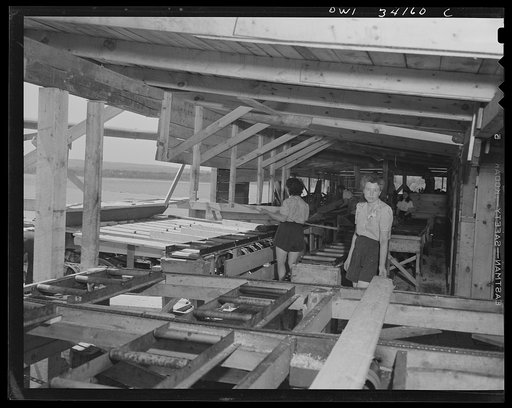 Untitled photo, possibly related to: Turkey Pond, near Concord, New Hampshire. Women workers employed by a U.S. Department of Agriculture timber salvage sawmill. As a board comes away from the edges, Mrs. Lucy DeGreen, right, taking away from the edges and putting them on a conveyor to be sawed into