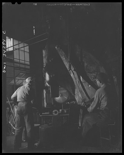 Untitled photo, possibly related to: New Britain, Connecticut. Peter Juliana, steam-hammer operator and Bidwell Hughes, steam-hammersmith, working with a Chamers-ring steam hammer at the Fafnir Bearing Company