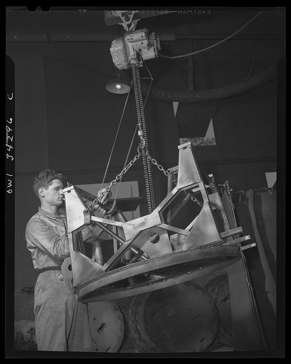New Britain, Connecticut. A worker at the Landers, Frary and Clark plant moving an anti-aircraft machine gun mount by a motor crane
