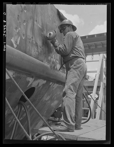 Bushing a welded section on the hull of a cargo vessel at the Higgins shipyards. New Orleans, Louisiana