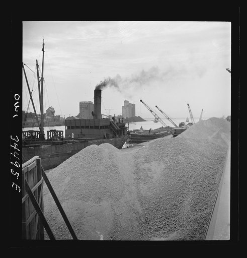 Untitled photo, possibly related to: Oswego, New York. Unloading bauxite from a barge onto a Canadian boat which has come up through the inland waterways from Dutch Guiana
