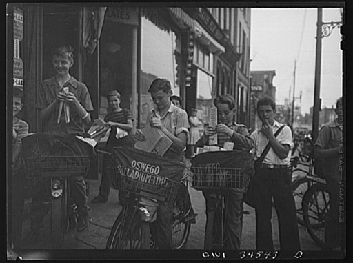 Untitled photo, possibly related to: Oswego, New York. The Palladium-Times, a daily afternoon paper, is distributed by these boys on bicycles. The congregate outside the newspaper office at 4 p.m. and fold papers before starting on their routes