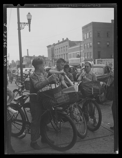 Oswego, New York. The Palladium-Times, a daily afternoon paper, is distributed by these boys on bicycles. The congregate outside the newspaper office at 4 p.m. and fold papers before starting on their routes