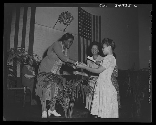 Washington, D.C. Mrs. Mary McLeod Bethune, President of the National Council of Negro women, presenting certificates to hostesses for USO duty, at the Phyllis Wheatley YWCA on Rhode Island Avenue. Facing the camera is Miss Dorothy Height, Director of the YWCA