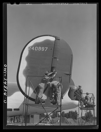 Warner Robins, Georgia. Air Service Command, Robins Field. Aircraft mechanics and ordnance men working on the rudder and tail guns of a B-24