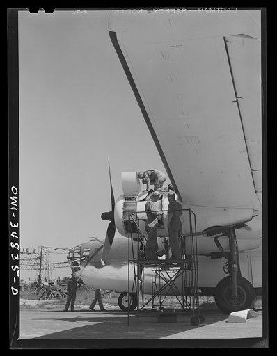 Warner Robins, Georgia. Air Service Command, Robins Field. Mechanics removing the cowling of one of the engines of a B-24 bomber