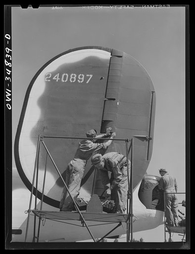 Warner Robins, Georgia. Air Service Command, Robins Field. Aircraft mechanics and ordnance men working on the rudder and tail guns of a B-24