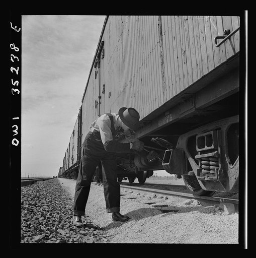 Texico, New Mexico. Conductor E.K. Hill inspecting the Atchison, Topeka and Santa Fe Railroad train in a siding