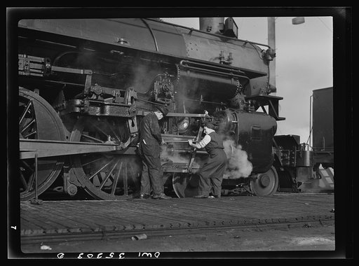 San Francisco, California. A woman railroad worker learning how to grase an engine wheel