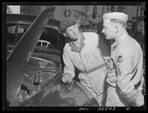Bowman, South Carolina. Sergeant John Riley, home on leave, is with the 25th service group, Air Service Command. Before enlisting in the Army, he had worked for many years in his father's garage. Here he is discussing an engine problem with his father