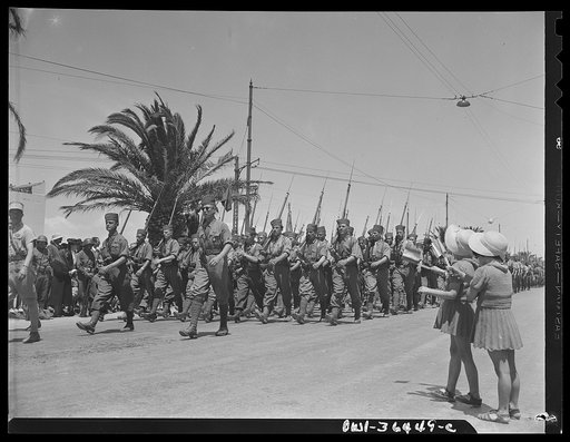 Tunis, Tunisia. Two French children waving as French troops march in the Allied victory parade along Avenue Gambetta
