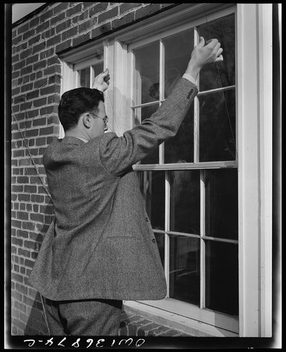 Washington, D.C. Installing a "Victory" storm pane, or extra pane of glass on a home window as a war-time fuel conservation measure. Placing the victory storm pane against the window frame