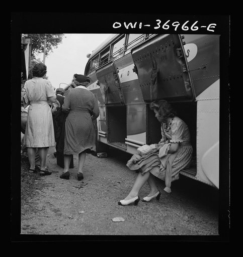 A girl passenger sitting in a baggage compartment while she is waiting for the driver to finish unloading the bags from a Greyhound bus that broke down at a small town in Pennsylvania