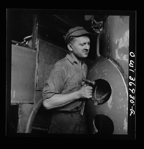 Pittsburgh, Pennsylvania. A mechanic straightening a bent fender on a bus at the Greyhound garage