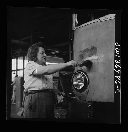 Untitled photo, possibly related to: Pittsburgh, Pennsylvania. A girl cleaner scraping the paint from a bus which is to be repainted at the Greyhound garage