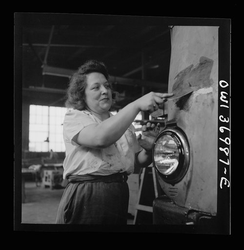 Untitled photo, possibly related to: Pittsburgh, Pennsylvania. A girl cleaner scraping the paint from a bus which is to be repainted at the Greyhound garage