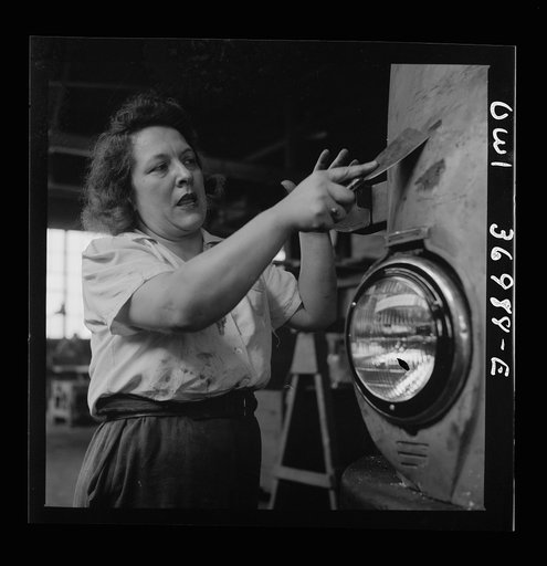 Pittsburgh, Pennsylvania. A girl cleaner scraping the paint from a bus which is to be repainted at the Greyhound garage