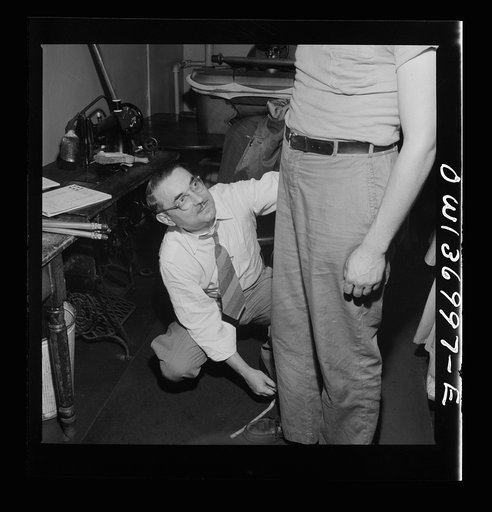 Pittsburgh, Pennsylvania. Isidore Rubinoff, the tailor for the Greyhound Company, measures a new driver for his uniform