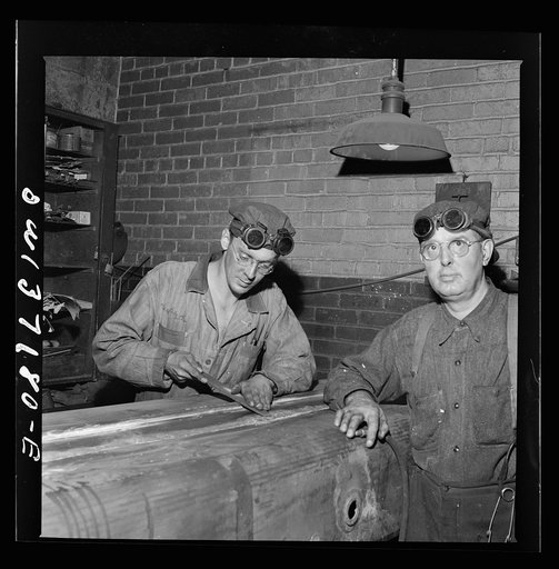 A mechanic working on a gas tank at the Greyhound garage