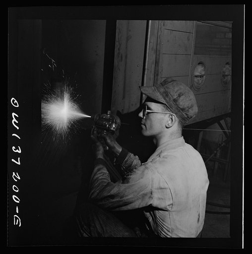 Untitled photo, possibly related to: Pittsburgh, Pennsylvania. A mechanic metalizing a part in the machine shop at the Greyhound garage. This is one of the new salvage operations for worn parts undertaken since the war