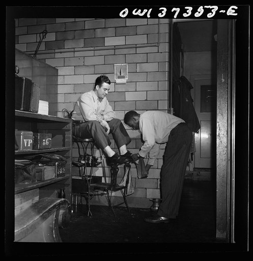 Pittsburgh, Pennsylvania. A Greyhound driver getting his shoes shined by a porter at the garage