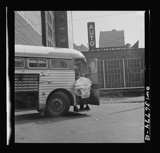 Chicago, Illinois. A pillow man at the Greyhound bus terminal taking used pillows from a bus that has just come in