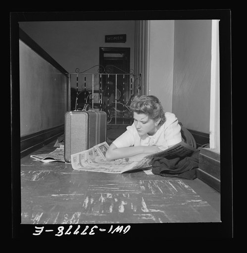 Louisville, Kentucky. A bus passenger reading the Sunday comics, which, since all the benches were full, she spread on the floor to sleep on while waiting from 11 p.m. to 8 a.m. for a bus in the Greyhound bus station. She is on her way to Nebraska to enroll in a nursing school