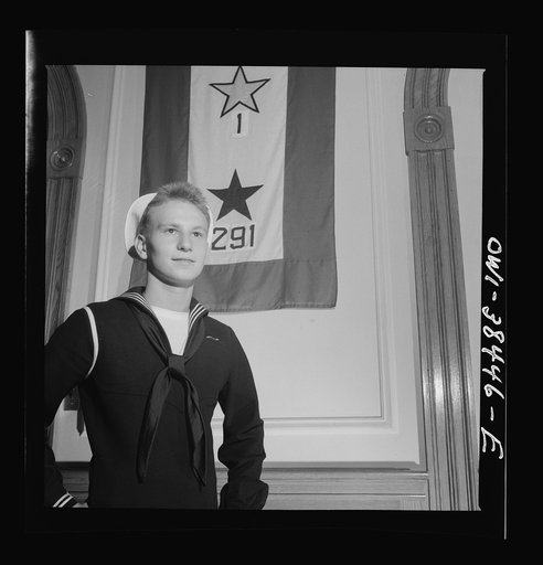Washington, D.C. A sailor who left Woodrow Wilson High School in June, 1943, standing in front of the school's service flag