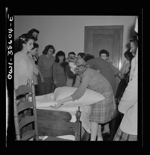 Washington, D.C. Home management students at Woodrow Wilson High School giving a demonstration in bedmaking. There is a model bedroom, living room, kitchen, and laundry for use by home economics students