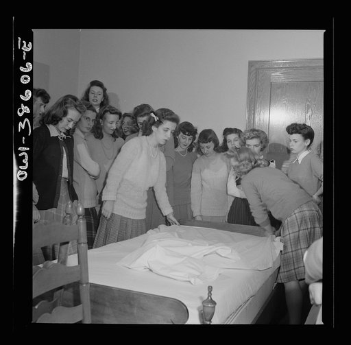 Washington, D.C. Home management students at Woodrow Wilson High School giving a demonstration in bedmaking. There is a model bedroom, living room, kitchen, and laundry for use by home economics students